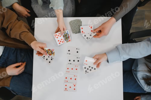 Preview: Friends playing cards on white table, having fun together