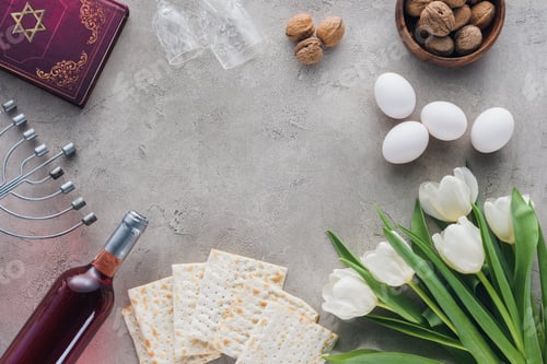 Preview: top view of traditional book with text in hebrew and matza on concrete table