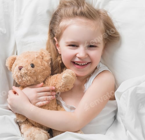 Preview: Girl holding her brown teddy, in bed