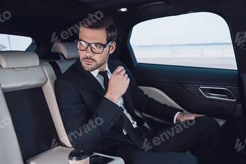 Preview: Contemplation. Thoughtful young man in full suit looking away while sitting in the car