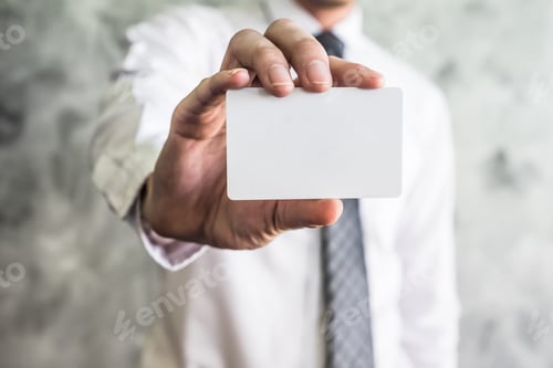 Preview: Close up of businessman holding white blank card on grunge background.