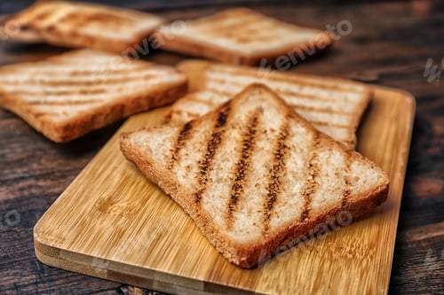 Preview: Tasty toasted bread on wooden board, closeup