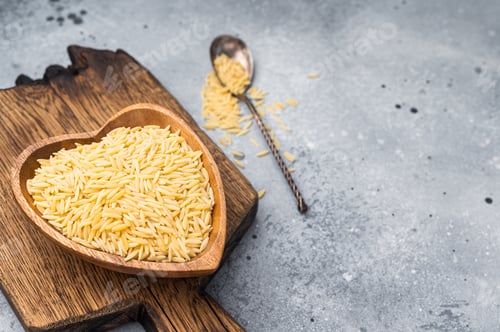 Preview: Raw Orzo pasta, uncooked dry Italian risoni in a bowl. grey background. top view