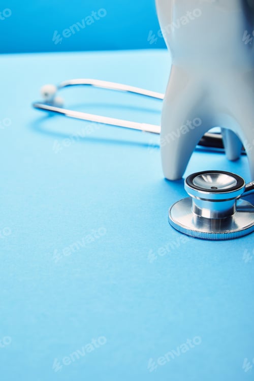 Preview: close up view of tooth model and stethoscope on blue backdrop