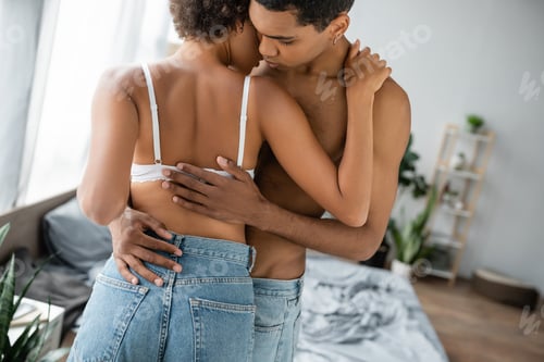 Preview: young and shirtless african american man embracing seductive girlfriend in bra and jeans