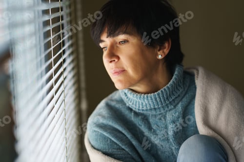 Preview: Happy middle-aged woman with nostalgic look as she gazes out the window