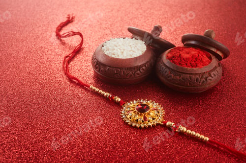 Preview: Raksha Bandhan. Rakhi string, Rice Grains and Kumkum on red background.