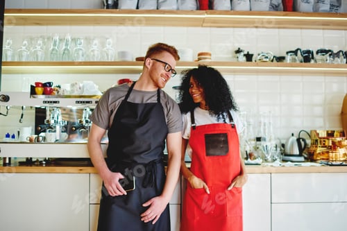 Preview: Pleased multiethnic employee of cafe in aprons