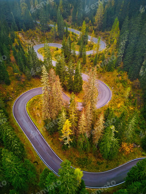 Preview: Aerial drone view of Dolomites Mountains in autumn season with forest. Serpentine road. Italy