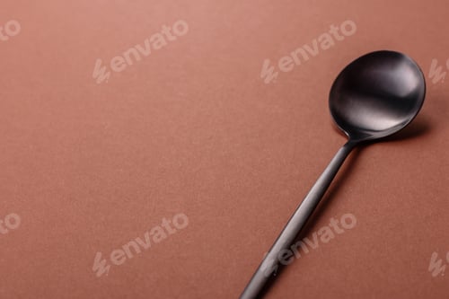 Preview: Empty metal spoon on a monochrome brown background