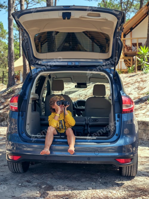 Preview: Boy sitting in car and looking through binoculars