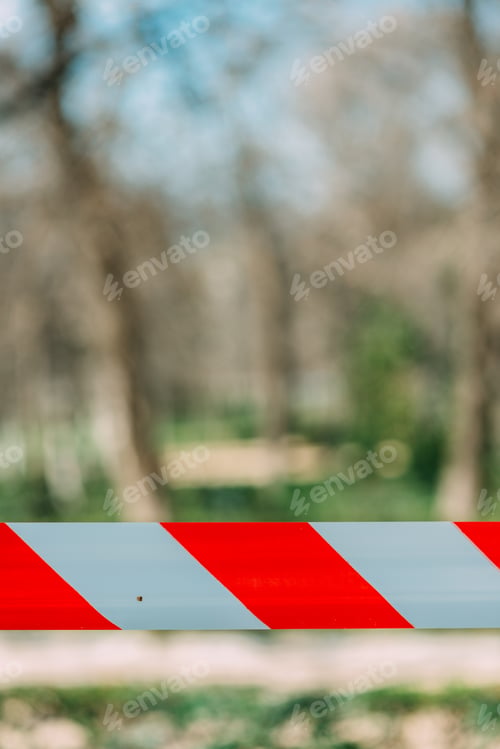 Preview: Vertical shot of a red and white barricade tape in the park