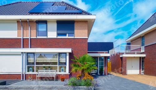 Aperçu: Newly build houses with solar panels attached on the roof against a sunny sky
