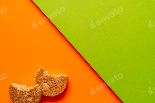 Preview: Two bitten cookies on bright orange and green paper background