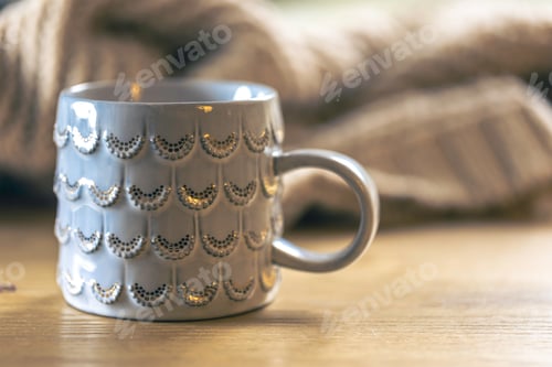 Preview: Close-up, shiny gray cup on a blurred background with a knitted element.