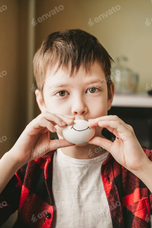 Preview: funny photo of a boy with a painted smile on the eggs. An egg with a painted smile.