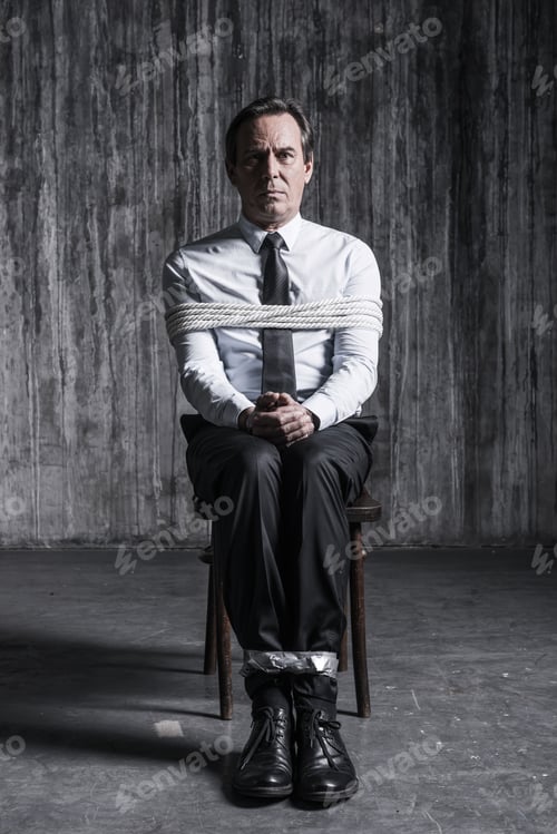 Preview: Feeling hopeless. Shocked businessman sitting at the chair and shouting while being tied up