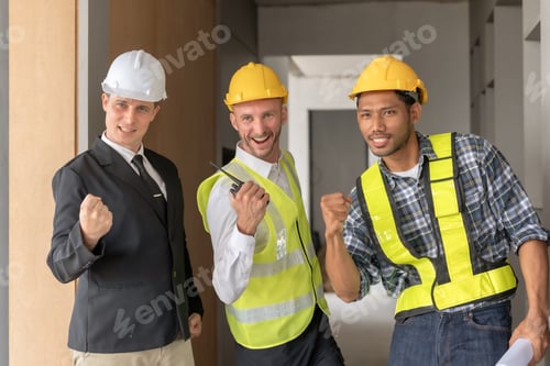 Preview: Three happy men in helmets and safety vests are at a work site, smiling and raising their fists up.
