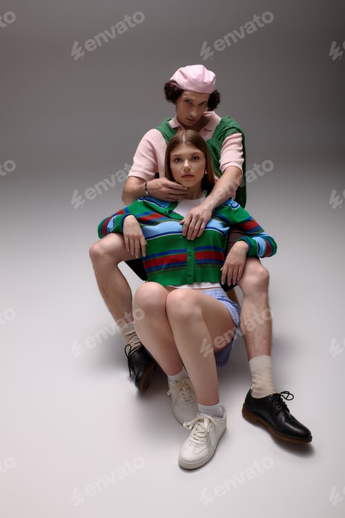 Preview: Stylish young couple showcase chic outfits in grey studio setting