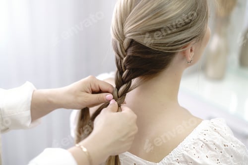 Preview: a hairdresser making a braid to a young fashion model, backstage preparation