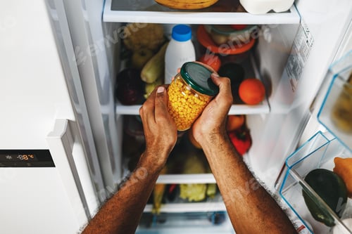 Preview: Male hands taking canned corn jar from fridge