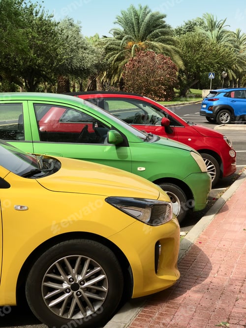Preview: Colorful cars parked in the order: yellow, green, red, blue. With palm trees on the background