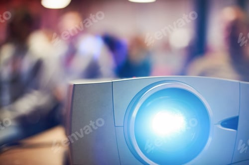 Preview: Close-up multimedia projector with blurred people background.