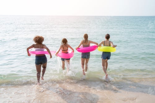 Preview: Group of teenage with floaty on the beach having fun in a sunny day.