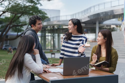 Preview: Young asian students discussing project using laptop outdoors