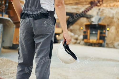 Preview: Rear view. Worker in professional uniform is on the borrow pit at daytime