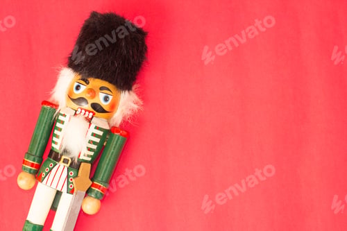 Preview: Interesting beautiful christmas nutcracker soldier on red colored paper surface texture with copy