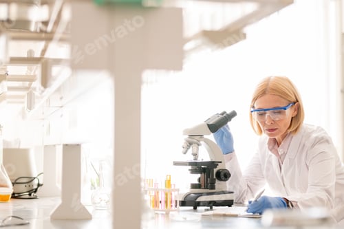 Focused Woman Researching with Microscope in Bright Lab