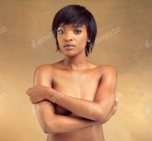 Preview: All allure. Studio portrait of a beautiful shirtless young woman against a brown background.