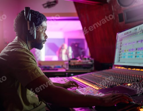 Preview: Black man, studio recording and music job in night with headphones, computer or focus by mixing con
