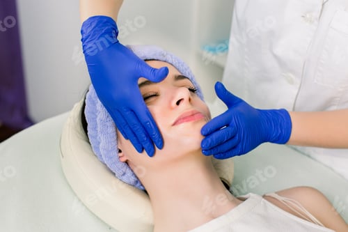 Preview: Beautiful young Caucasian woman relaxing with face massage and cosmetology procedures at beauty spa