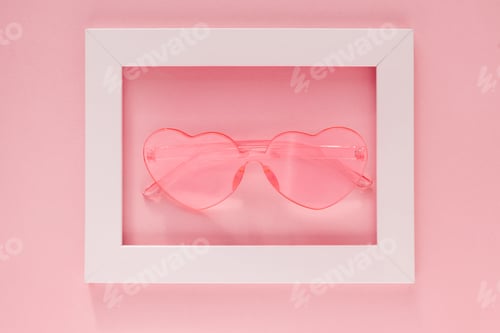 Preview: Pink heart-shaped glasses in a white frame on a pink background.