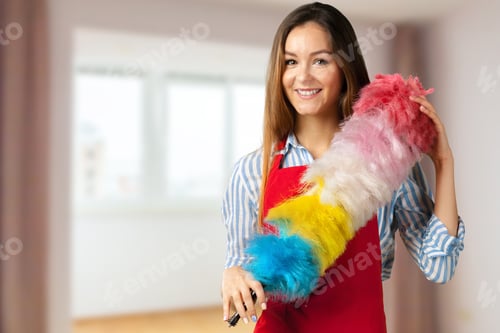 Preview: Woman cleaning a room with a colorful duster in a bright space during daytime