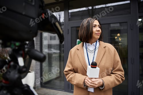 Preview: A multiracial female journalist reports news outside a modern building