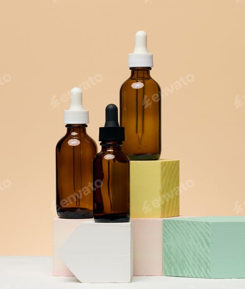 Preview: Various glass bottles with pipettes containing cosmetic serums or oils. Beige background