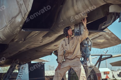 Preview: Mechanic in uniform carries out maintenance of a war fighter-interceptor in an open-air museum.