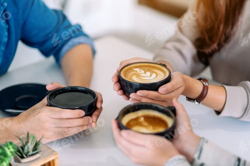 Preview: Closeup image of people holding and enjoyed drinking coffee on the table in cafe