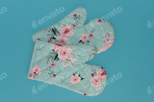 Preview: Kitchen glove potholders with flower patters isolated on a blue.