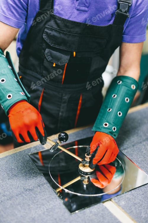 Preview: Glazier worker cutting glass with compass glass cutter in a workshop.