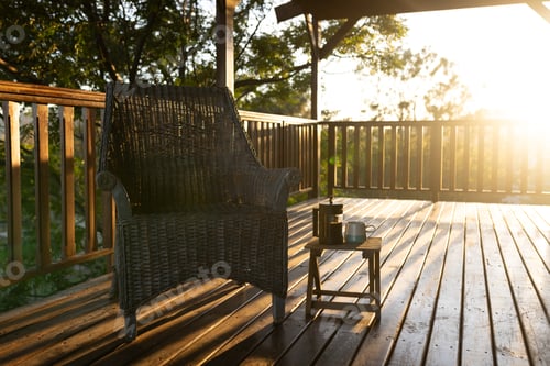 Preview: Balcony of log cabin with armchair and mug of coffee on sunny day