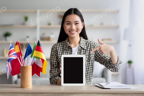Preview: Happy asian woman pointing at pad with blank screen