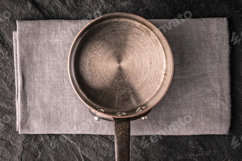 Preview: Metal pan on the dark stone table top view