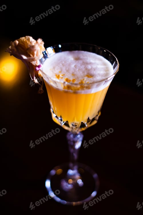 Preview: Vertical shot of an orange cocktail in a a glass on a dark blurry background