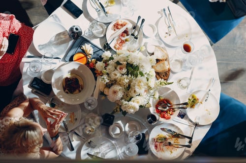 Preview: top view of a woman sitting at a table with bouquets of flowers in restaurants half-eaten dishes on