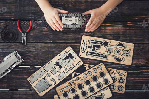 Preview: Top View Of The Table Covered With Pieces Of Wooden Constructor And Hands Of Child Holding Metal