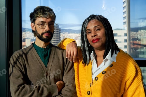 Preview: Two business people posing together in modern office with city view.
